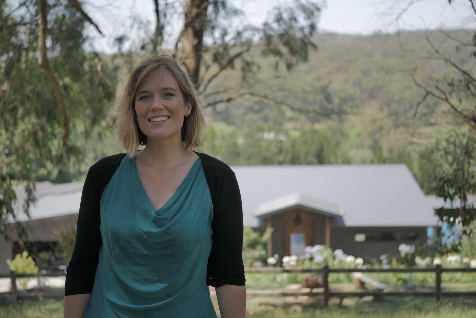 Dr Gayatri Rachel Anderson smiling in a garden in front of mountains